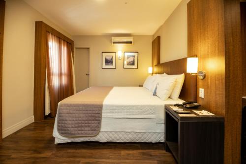 a hotel room with a large bed and a desk at Porto da Ilha Hotel in Florianópolis