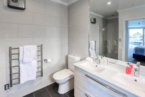 a white bathroom with a toilet and a sink at Marsden Lake Resort Central Otago in Cromwell