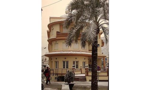 a palm tree in front of a large building at HOTEL LA FONDA DE DON GONZALO in Cenes de la Vega