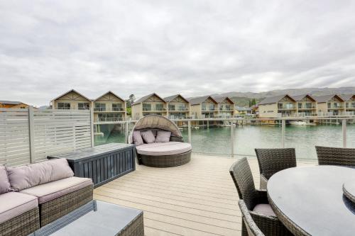 a deck with chairs and tables on a body of water at Marsden Lake Resort Central Otago in Cromwell