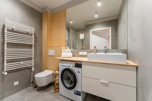 een badkamer met een wasmachine en een wastafel bij Apartament SUBMARINE SurfingBird Dźwirzyno in Dźwirzyno