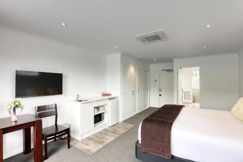 a bedroom with a bed and a desk and a tv at Marsden Lake Resort Central Otago in Cromwell