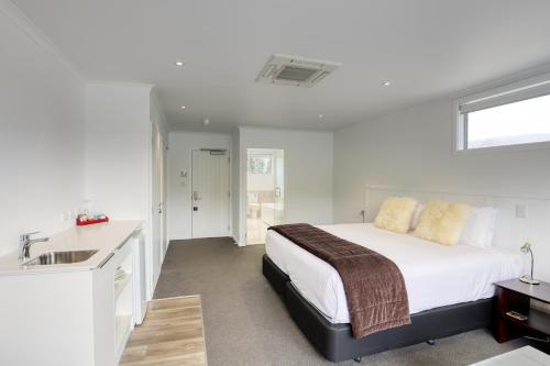 a bedroom with a bed and a sink and a bathroom at Marsden Lake Resort Central Otago in Cromwell