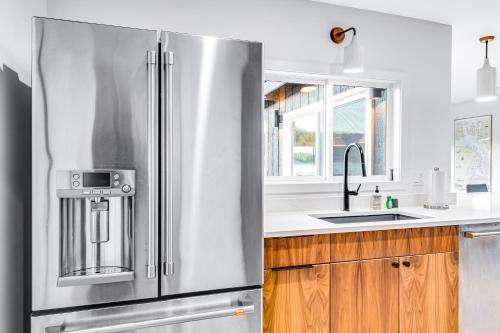 a stainless steel refrigerator in a kitchen with wooden cabinets at Lopez Island Mud Bay Waterfront home in Islandale