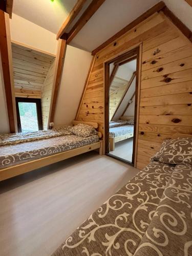 a bedroom with two beds and a mirror at Planinska Koliba ABA-TARA in Bajina Bašta