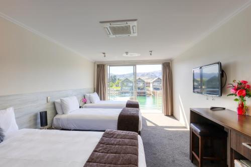 a hotel room with two beds and a tv at Marsden Lake Resort Central Otago in Cromwell