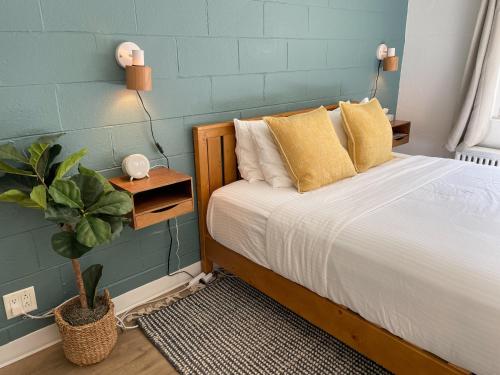 Un dormitorio con una cama con almohadas amarillas y una planta en Al & Sally's Motel en Michigan City