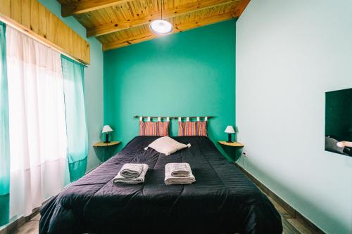 ein Schlafzimmer mit einem schwarzen Bett und einer blauen Wand in der Unterkunft OHANA in Sierra de la Ventana