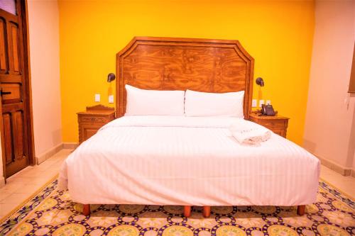 a bedroom with a large bed with a wooden headboard at Hotel Real Toledo by Kavia in Mérida