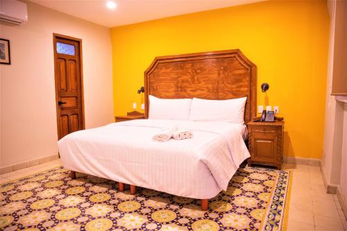 a bedroom with a large bed and a yellow wall at Hotel Real Toledo by Kavia in Mérida