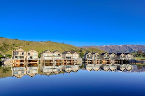 a row of houses on the water with their reflections at Marsden Lake Resort Central Otago in Cromwell