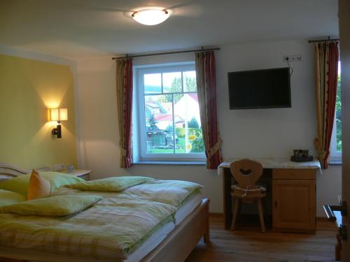 Schlafzimmer mit einem Bett, einem Fenster und einem Schreibtisch in der Unterkunft Ferienhof Rösch in Bad Wurzach