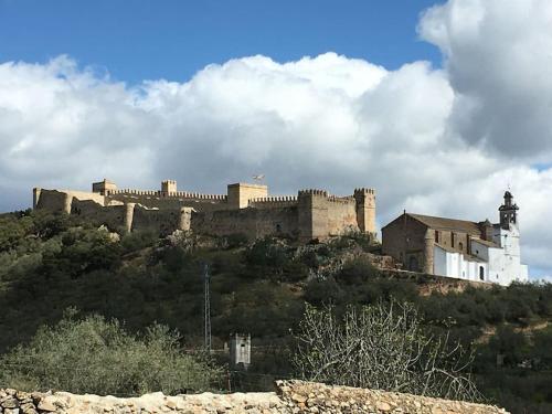 een groot kasteel bovenop een heuvel bij Agradable casa rural con suelos de madera in Santa Olalla del Cala