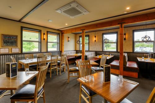 a restaurant with wooden tables and chairs and windows at Marsden Lake Resort Central Otago in Cromwell