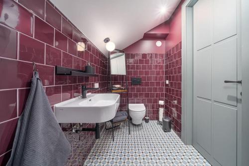 a red tiled bathroom with a sink and a toilet at Bright Designer Mansard in city centre in Rīga
