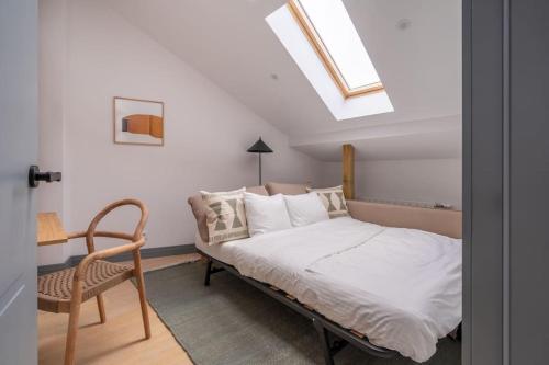 a bedroom with a bed and a chair and a skylight at Bright Designer Mansard in city centre in Rīga