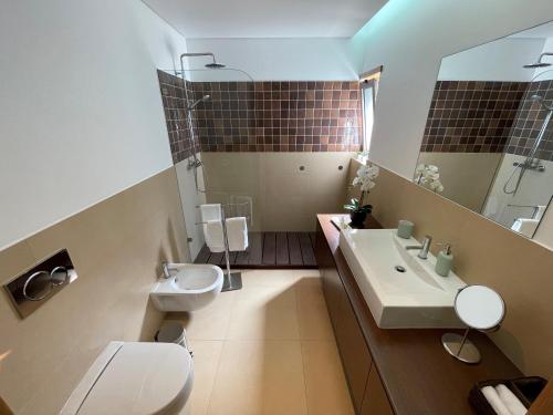 ein Badezimmer mit einem Waschbecken, einem WC und einem Spiegel in der Unterkunft Albufeira Lux Apartment in Albufeira