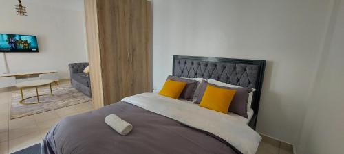a bedroom with a large bed with yellow pillows at Anmeg Deluxe Rooftop Studio Apartment in Nairobi