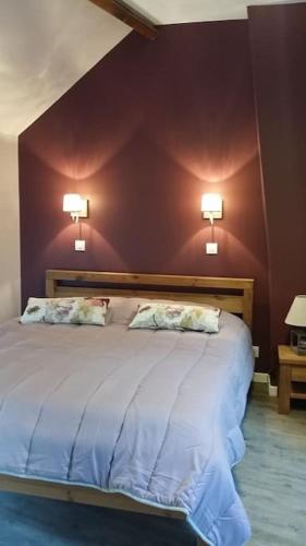 - une chambre avec un grand lit et deux lumières sur le mur dans l'établissement Gîte des Avaux- prés de Paris, à Champcueil