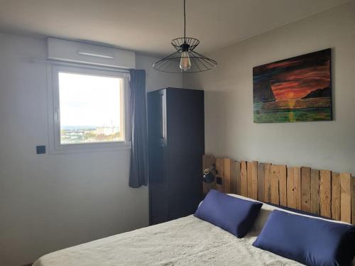 une chambre avec un lit avec des oreillers bleus et une fenêtre dans l'établissement Magnifique appartement, à Salon-de-Provence