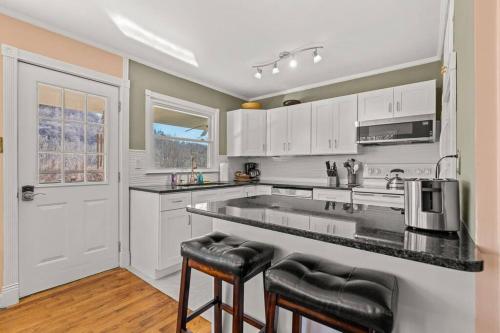 WeavervilleにあるSerenity Views Retreat - Close to City and Parkway!の白いキャビネットと黒いカウンタートップを備えたキッチン
