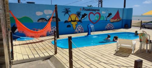 uma piscina com pessoas com um mural em Pousada Lá Na Praia em São José da Coroa Grande