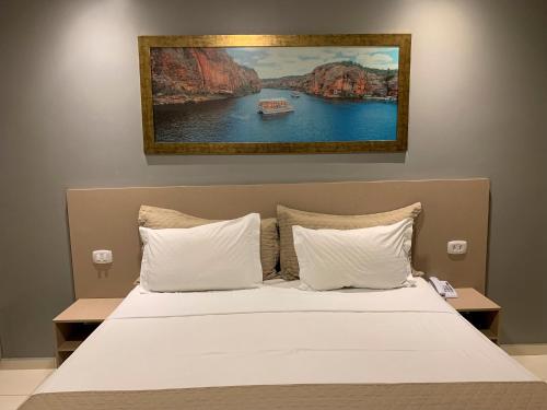 a bed with white pillows and a painting on the wall at Dunen Hotel in Piranhas