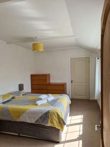 um quarto com uma cama com um cobertor amarelo e cinzento em Resthaven Cottage em Mablethorpe