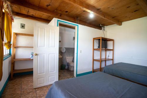 a room with two beds and a door to a bathroom at Hotel y Rest. las Cristalinas in San Pedro La Laguna