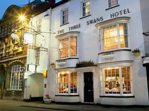 a white building with the three swans hotel on a street at The Three Swans Hotel, Market Harborough, Leicestershire - The Coaching Inn Group in Market Harborough