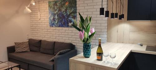 una sala de estar con sofá y una botella de vino y flores en Be my Guest- Fontany Luxury Apartment Metro Wi-Fi free parking zone, en Varsovia