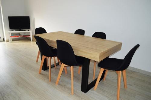 mesa de madera con sillas negras y TV en Market Apartment - VPA, en Vila Praia de Âncora