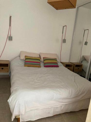1 dormitorio con 1 cama blanca y 2 almohadas en departamento tres cerritos en Salta