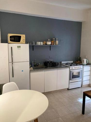 una cocina con electrodomésticos blancos y una mesa. en departamento tres cerritos en Salta