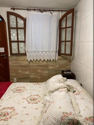 a bed in a bedroom with a window and a bedspread at Estúdio ( Kitnet ) confortável in Ouro Preto