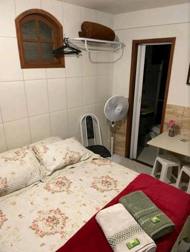 a bedroom with a bed and a table and a fan at Estúdio ( Kitnet ) confortável in Ouro Preto