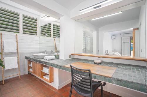 La salle de bains est pourvue d'un comptoir avec un lavabo et une chaise. dans l'établissement Villas Manzelle - Luxury villas on the beach, au Vauclin