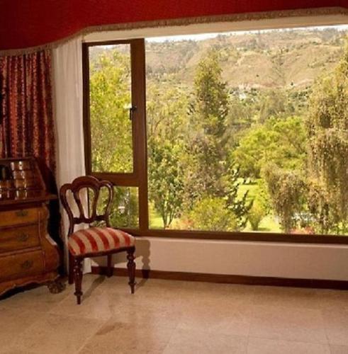 a room with a chair and a large window at Uzhupud Garden Hotel & Lodge in Paute