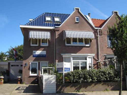 a brown brick house with white awnings on it at Pension Zandvoort aan Zee in Zandvoort