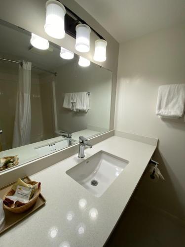 baño con lavabo y espejo grande en Chalet Continental Motel, en Valemount