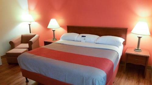 Cette chambre comprend un grand lit et une chaise. dans l'établissement Motel 6-Maryland Heights, MO, à Maryland Heights