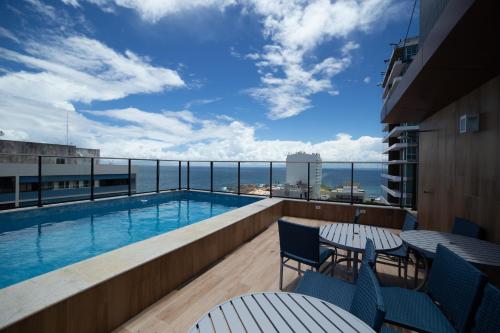 balcón con piscina y vistas al océano en LINDO FLAT NO FAROL DA BARRA, en Salvador