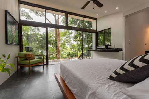 1 dormitorio con 1 cama, 1 silla y ventanas grandes en Costa Rican Jungle Experience, en Tinamaste