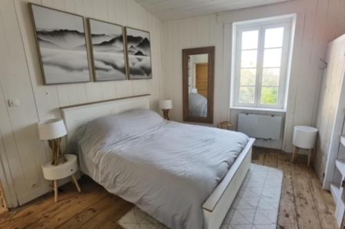 een slaapkamer met een groot wit bed en 2 ramen bij House in the center and near the beach in Rivedoux-Plage