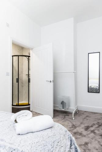 a white bedroom with a bed and a mirror at Warwick West in Barrow in Furness
