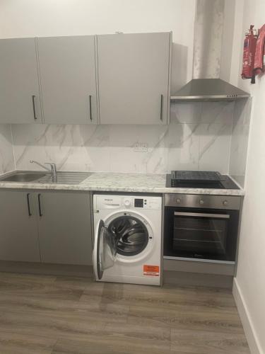 a kitchen with a stove and a washing machine at GOLDSTONE LONDON STUDIO WITH ACCESS TO GARDEN in Saint Mary Cray