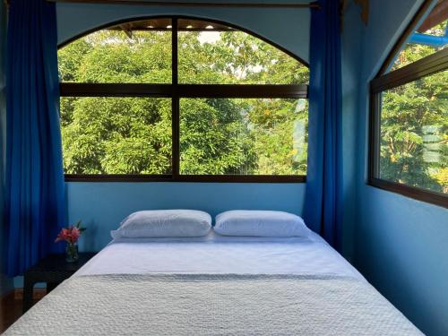 a blue bedroom with a bed and two windows at El Paraiso Azul in Ojochal