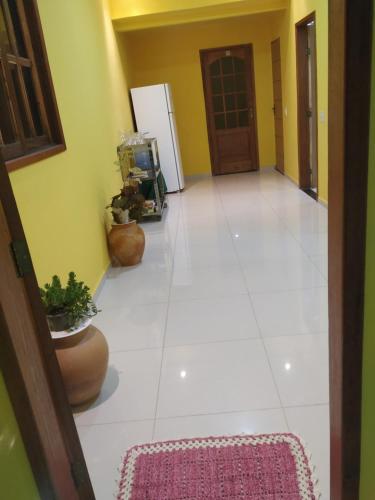 a hallway with a white tile floor and a refrigerator at Casa Calumbé do Vale, na vila do Vale do Capão in Vale do Capao
