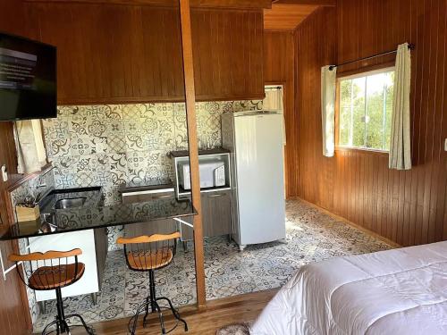 a kitchen with a refrigerator and a bed in a room at Pousada Lago do Amanhecer in Capão Alto