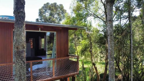a tree house with a swing in the woods at Pousada Lago do Amanhecer in Capão Alto
